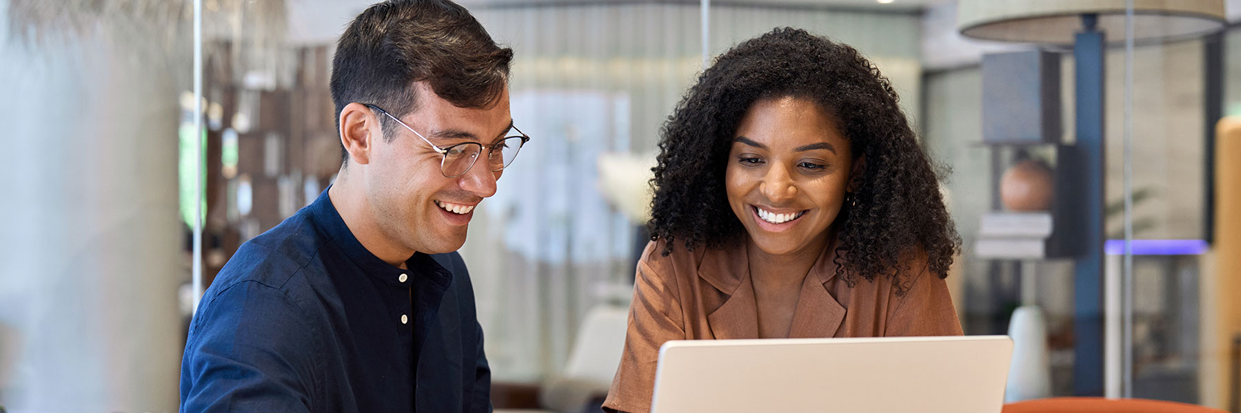 Smiling team professional employees working together on computer discussing online technology data solutions at work.