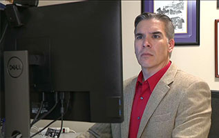 joshua vest sitting at desk looking at computer screen